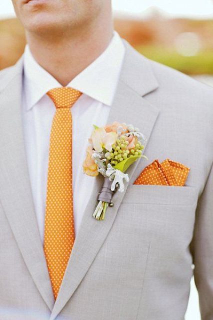 einen leichten grauen Anzug mit einem weißen Hemd und eine polka dot orange Krawatte und ein Taschentuch