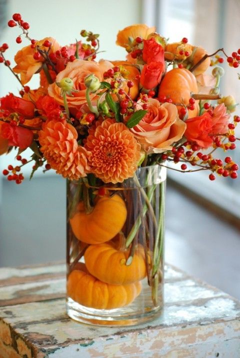 eine kühne floral arrangement in burnt orange und Kürbisse in der vase für eine Herbst-Hochzeit