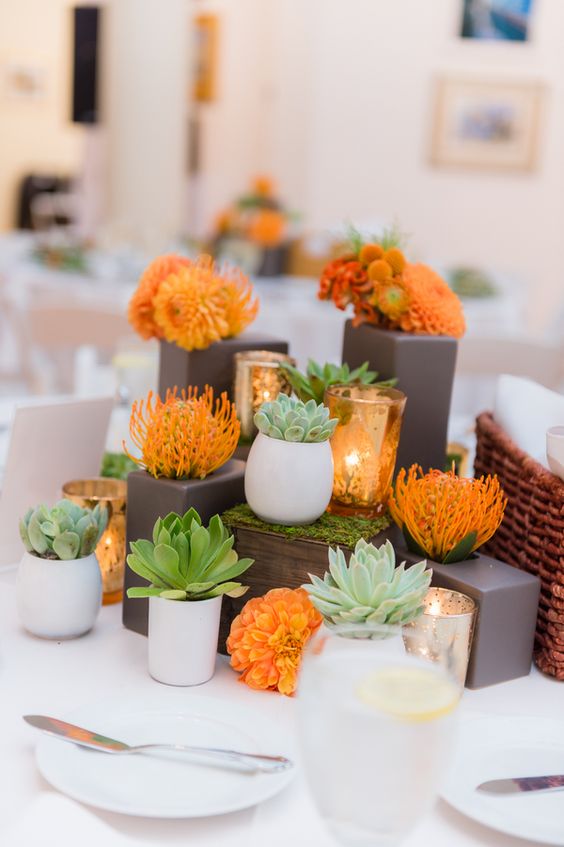 eine moderne Hochzeit Herzstück mit Sukkulenten und orange Blüten