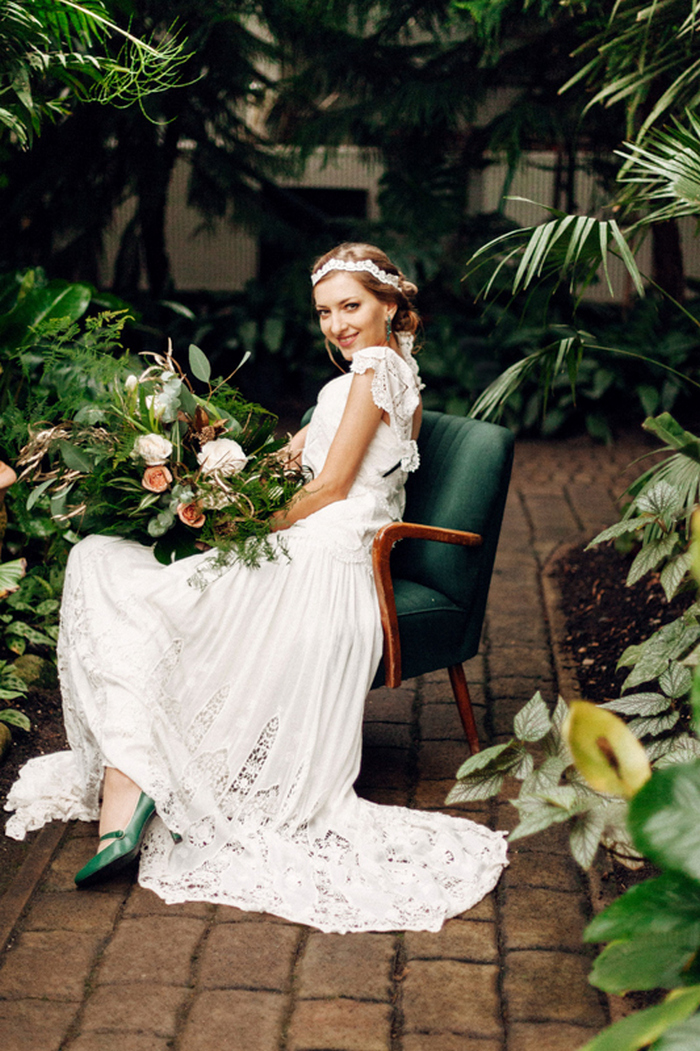Die Braut trug ein vintage-inspiriert Spitzen Kleid mit einem offenen Rücken, emerald Schuhe, Ohrringe und ein Spitzen Stirnband