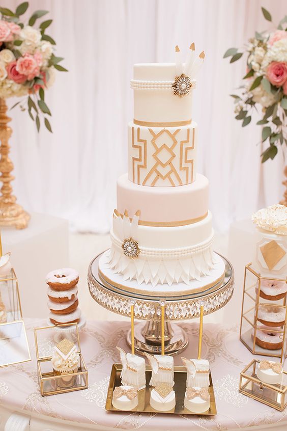 ein weiß und gold-Hochzeitstorte mit geo-Dekor, Blüten, Perlen, Federn und vintage-Broschen