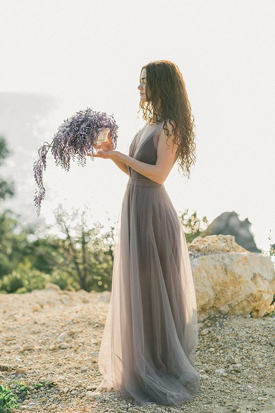 einem Grau-Lavendel-Hochzeits-Kleid mit tiefem Ausschnitt und einem Lavendel-Blumen-arrangement