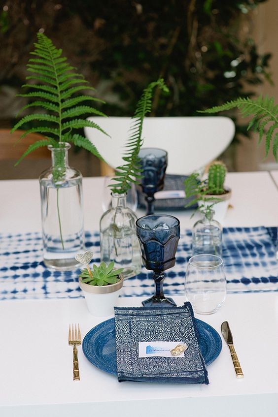 eine shibori-indigo Tischläufer, Gläser, bedruckte Servietten und Platten für einen boho Wald Hochzeit