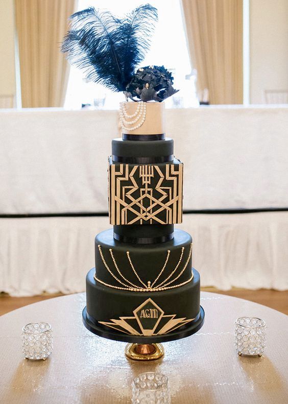 eine schwarze Hochzeitstorte mit unterschiedlich geformten Schichten, gold-geo Dekor, eine schwarz Zucker Blume und schwarzen Federn