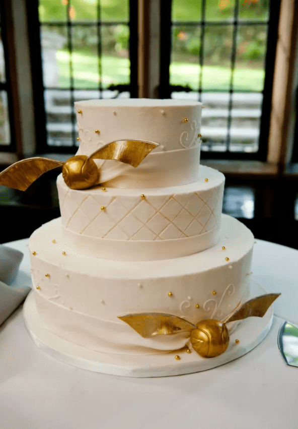 eine schicke Hochzeitstorte in weiß mit gold Perlen und gold snitches