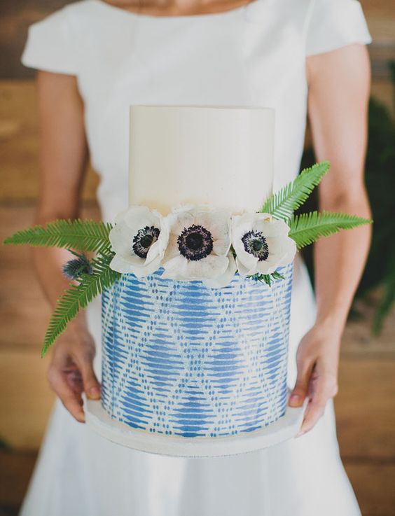 eine Hochzeitstorte mit einer cremigen Schicht und eine gemusterte indigo, garniert mit Blüten