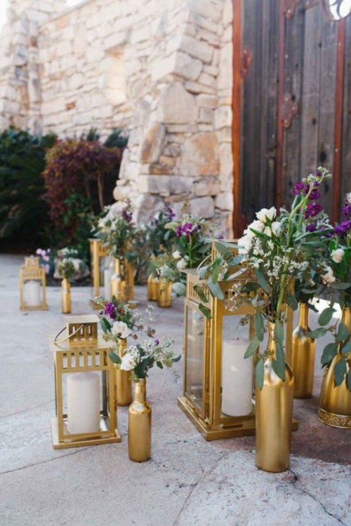 a beautiful wedding entrance decorated with gold bottles with bold blooms and matching gold candle lanterns is a lovely idea to rock