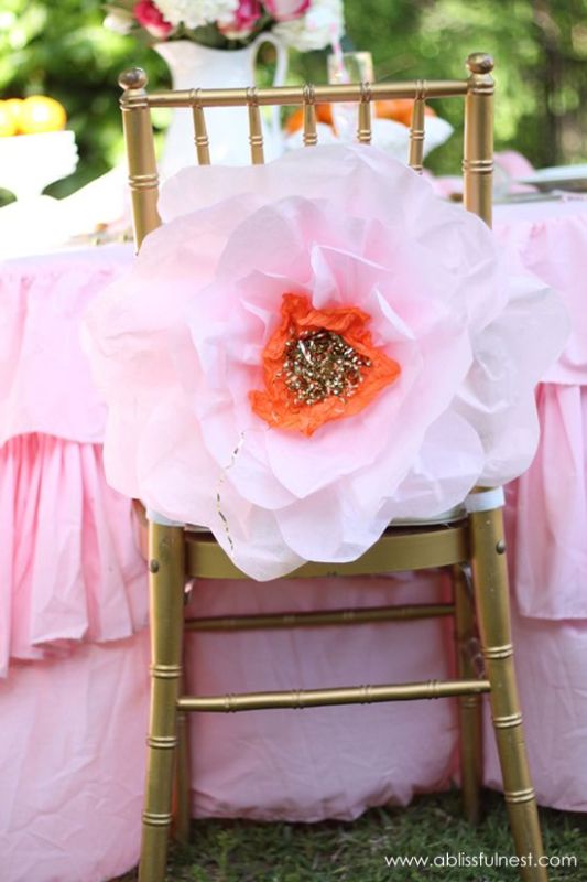 an oversized pink paper flower with a bright center will be a creative and bold decoration for a wedding chair