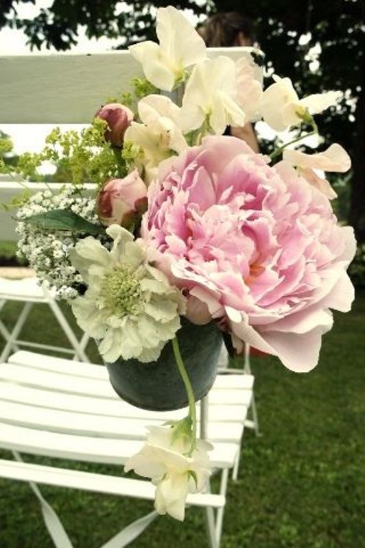 a white chair with neutral and an oversized pink bloom is a stylish idea for a spring or summer wedding