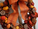 a pretty and catchy fall wedding wreath of nuts, yarn balls, berries and fruits plus an orange bow is a lovely idea for a fall harvest wedding