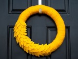 a bold yellow wreath wrapped with fabric and with some fabric leaves is an out-of-the-box idea for a fall wedding