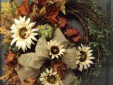 a rustic fall wreath with greenery, faux bright leaves, white blooms, faux pumpkins and gourds plus a ribbon bow and ribbons