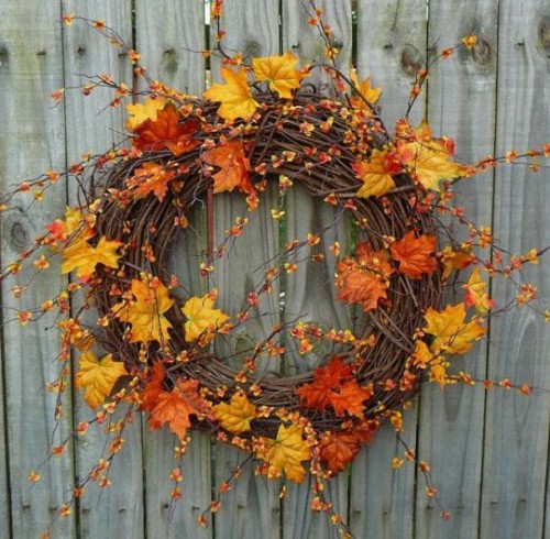 a fall wedding wreath of vine, with berries on long stems and bold fall leaves is a very cool and bold decor idea for a rustic celebration