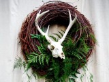a fall woodland wreath of vine, with lots of ferns and an animal skull is a mystical idea suitable also for a Halloween wedding