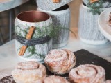 serve cinnamon buns and cover the mugs with cozies, greenery and cinnamon to make your dessert bar more relaxed and comfy