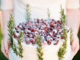 a winter boho wedding cake topped with sugared cranberries and greenery is a chic and stylish idea