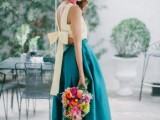 a bold bridesmaid look with a light yellow crop top with a tied back and an emerald full maxi skirt plus a statement necklace