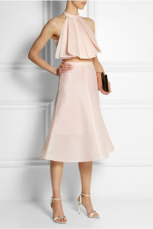 a trendy and bold look in blush with a pleated halter neckline crop top and a midi skirt plus white shoes and a black clutch