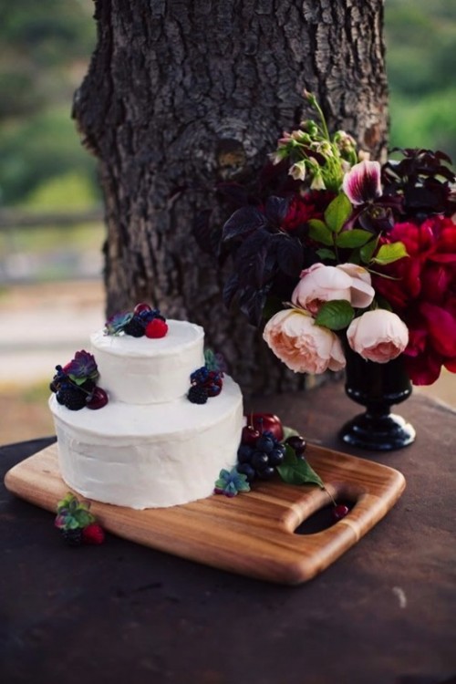 a white wedding cake topped with fresh berries and succulents is a cool idea for a fall wedding