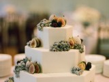 a white hexagon wedding cake topped with figs and grapes is a cool and lovely idea for a fall wedding