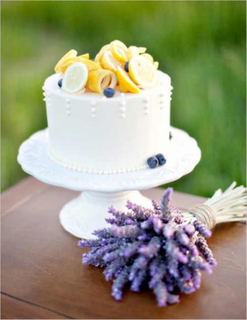 a sleek and plain white wedding cake topped with lemons and fresh blueberires is a cool idea for a summer wedding