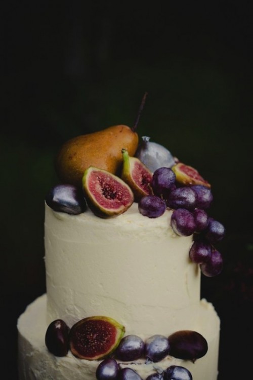 a plain white wedding cake topped with pears, figs, grapes is a chic and tasty solution for a fall wedding