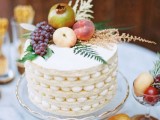 an oversized cookie wedding cake topped with grapes, greenery, apples and a gilded pomegranate is a cool solution for a wedding