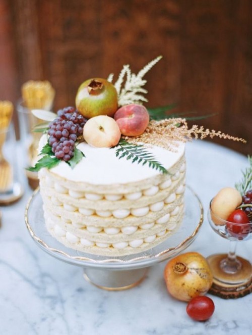an oversized cookie wedding cake topped with grapes, greenery, apples and a gilded pomegranate is a cool solution for a wedding