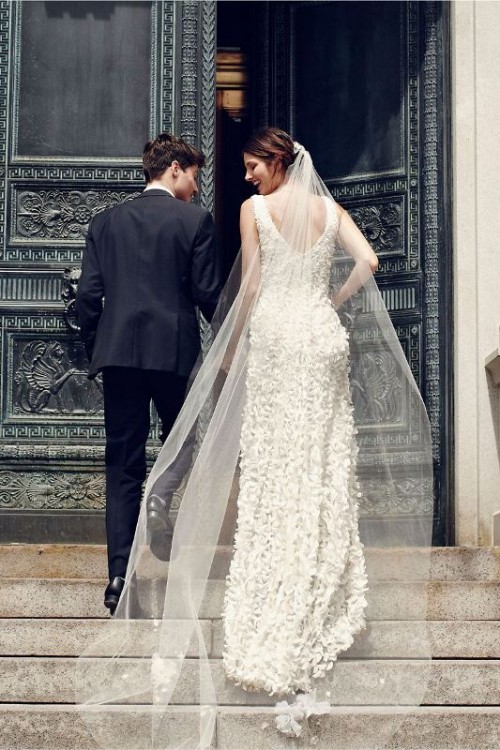 a super romantic A-line wedding dress with a cutout back, floral appliques, a train and no sleeves plus a neutral wedding veil