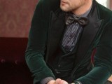 a green velvet tux with a waistcoat, a grey and white striped shirt, black pants and a black bow tie for a moody fall groom’s look