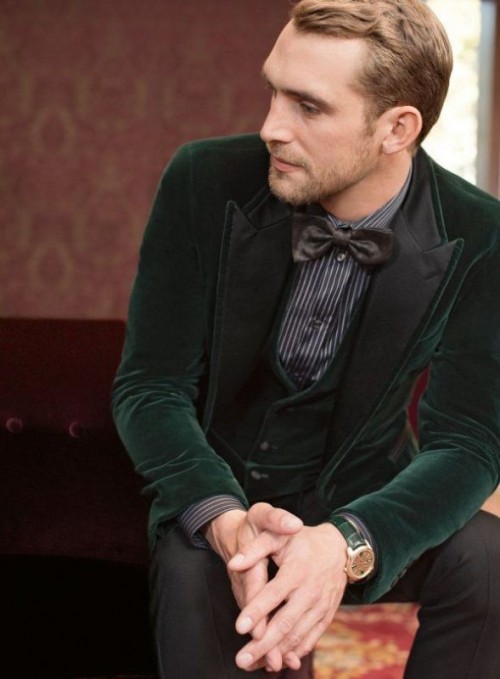 a green velvet tux with a waistcoat, a grey and white striped shirt, black pants and a black bow tie for a moody fall groom's look