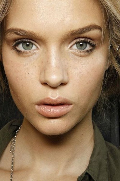 a nude makeup with a glossy nude lip, slight smokeys, accented eyebrows and highlighted skin