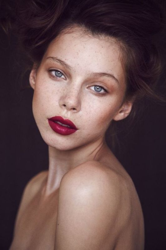 A dramatic makeup with a bold fuchsia lip, highlighted skin, and a touch of brown eyeshadow