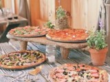 a rustic pizza bar done with a wooden table and comfortable stands for pizza plus potted herbs around