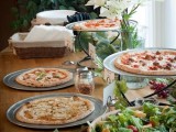 a cute rustic table with fresh blooms, pizzas, salad in a bowl, a basket with napkins