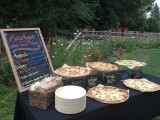 a simple pizza bar with a navy covered table, pizzas on wire stands and a chalkboard sign