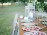 a simple and stylish pizza bar with pizzas on trays and lanterns plus chalkboard signs by the table