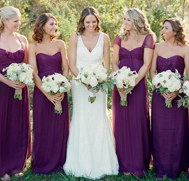 super bold purple maxi bridesmaid dresses with mismatching necklines, draped and tied bodices and pleated skirts are wow