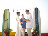 a creative tropical wedding altar of surf boards and bright blooms and greenery in jars is a cool option