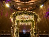a super lush floral wedding altar decorated with white blooms, greenery and lots of lights is breathtaking