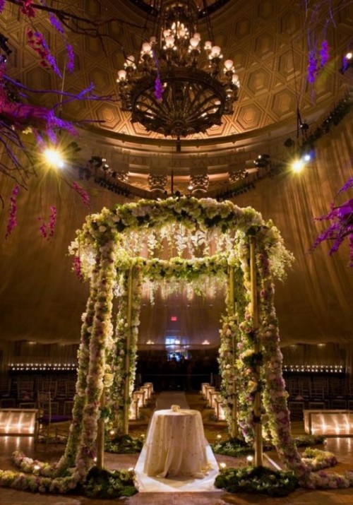 a super lush floral wedding altar decorated with white blooms, greenery and lots of lights is breathtaking