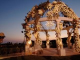 a super lush floral wedding altar with white blooms, vines, lights and a statement crystal chandelier