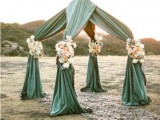 a unique wedding altar covered with fabric and decorated with neutral and pastel blooms looks very unusual