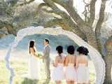 an arch of a living tree fully covered with white lace is a cool wedding decoration