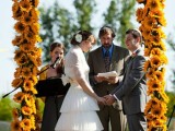 a unique wedding arch covered with sunflowers and with some bright fabric on top is a cool wedding altar for a rustic wedding