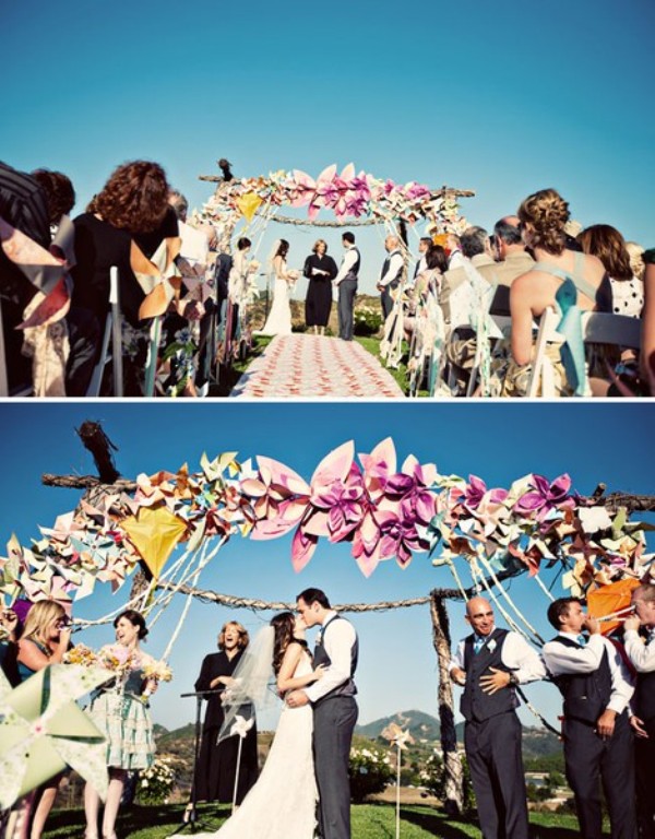 A wedding arch fully decorated with large and colorful paper flowers is a cool idea for a bright wedding