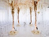 a unique wedding altar of birch trees, blooms and greenery hanging down, white petals and candles