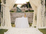 a super lush white floral altar and the aisle fully covered with white flower petals are a wedding ceremony setup