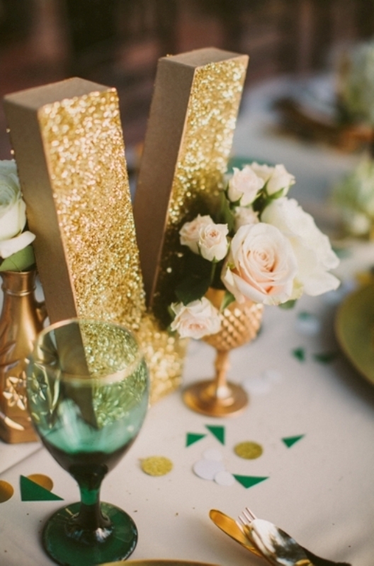 a gold glitter table number and a gold vase, green glasses for a chic and bright look of your reception table