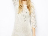 a boho lace off-white mini dress with a high neckline, short sleeves, a necklace and a floral crown for a boho bride